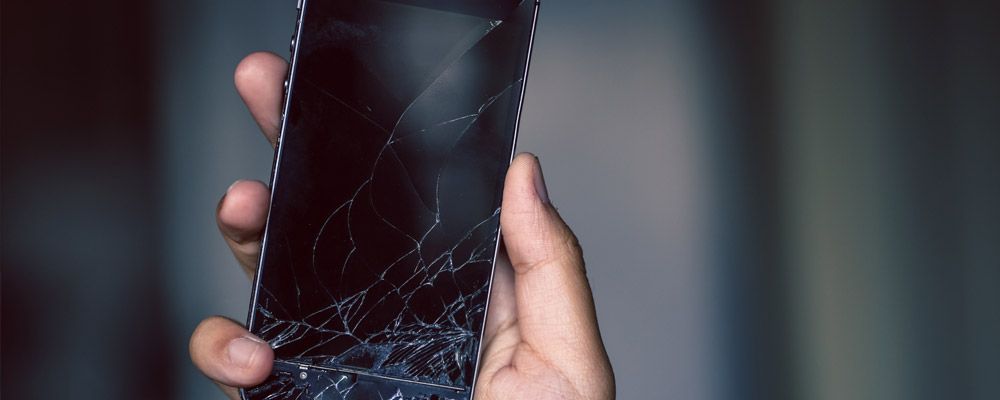 Image of a person holding a phone with a cracked screen